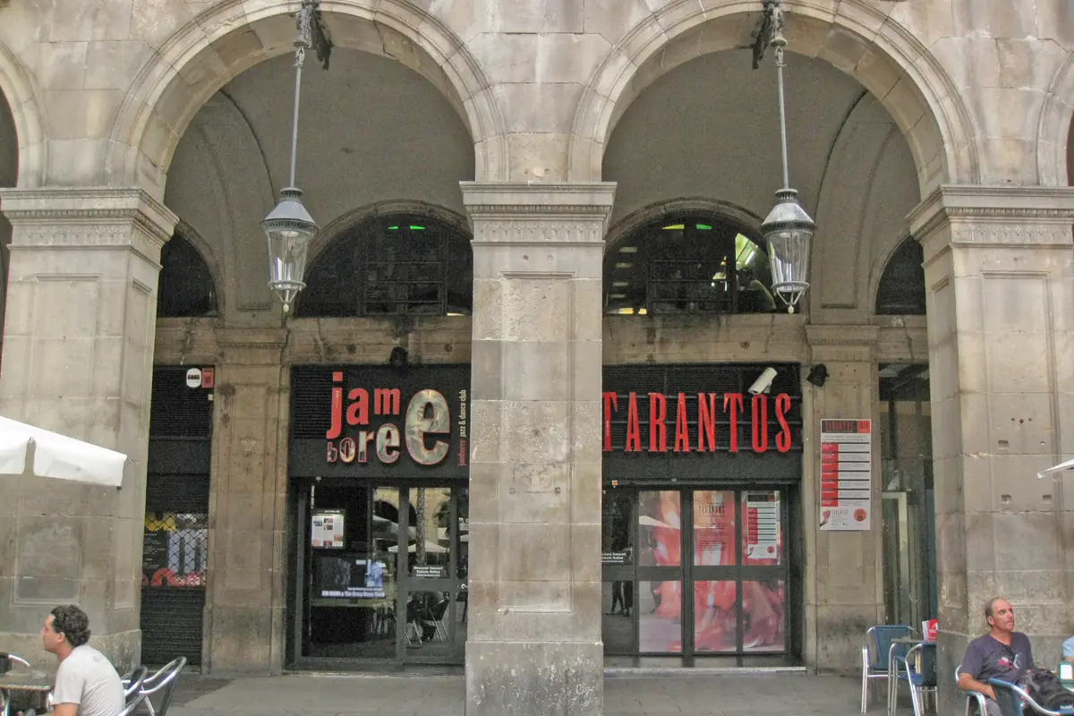 Arkáda na Plaça Reial 17 na fotografii z roku 2011, s červeným nápisem TARANTOS nad skleněnými dveřmi vedle sousedního hudebního klubu
